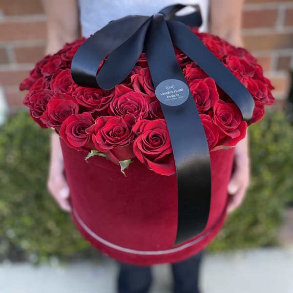 Large red rose bouquet in a round velvet box with a black ribbon