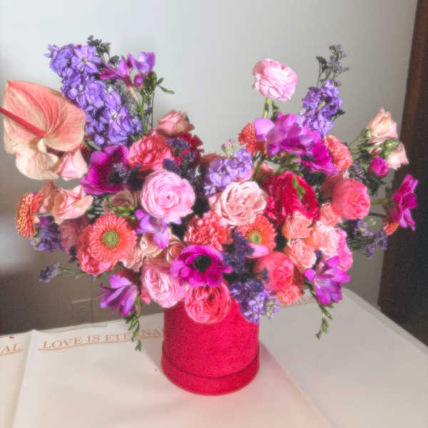 Colorful bouquet in a pink vase with pink, purple, and coral flowers