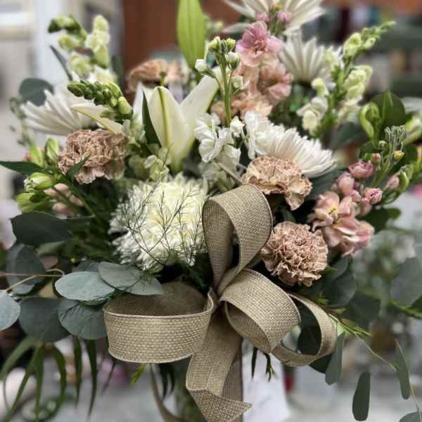 Bouquet of white and blush flowers with a tan ribbon bow