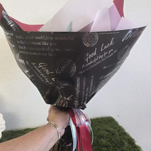 Wrapped bouquet with pink and white paper and ribbon