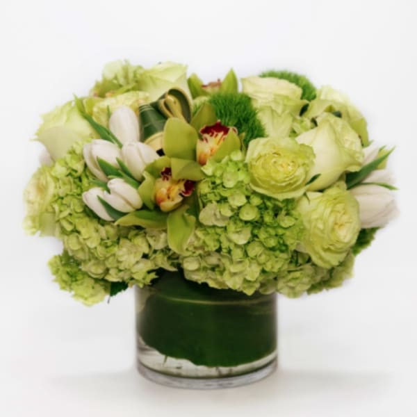 Green and white floral arrangement in a glass vase