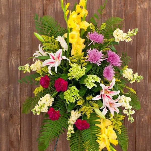 Tall mixed floral arrangement with yellow, pink, white, and purple blooms