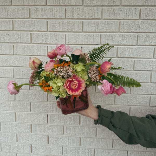 Handheld bouquet in a square glass vase with pink and green flowers