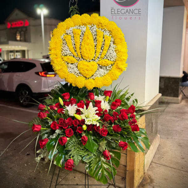 Standing floral tribute with red roses and a yellow flower emblem