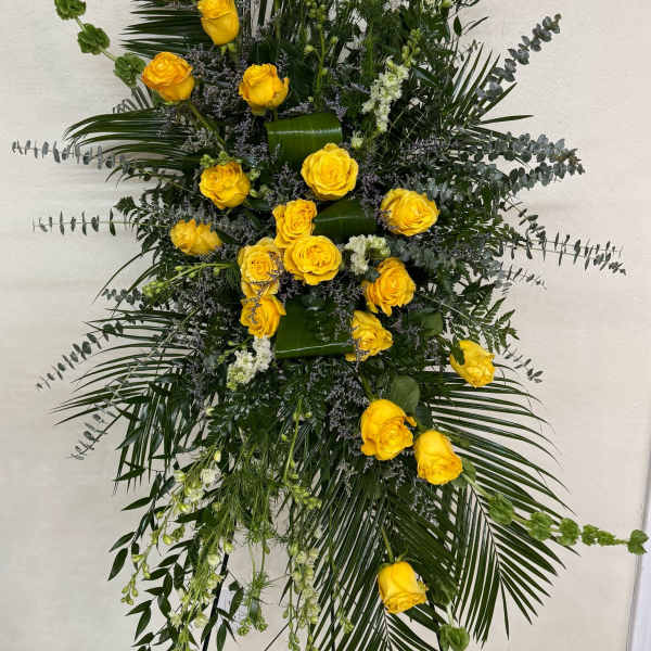 Tall floral spray with yellow roses and mixed greenery on a stand