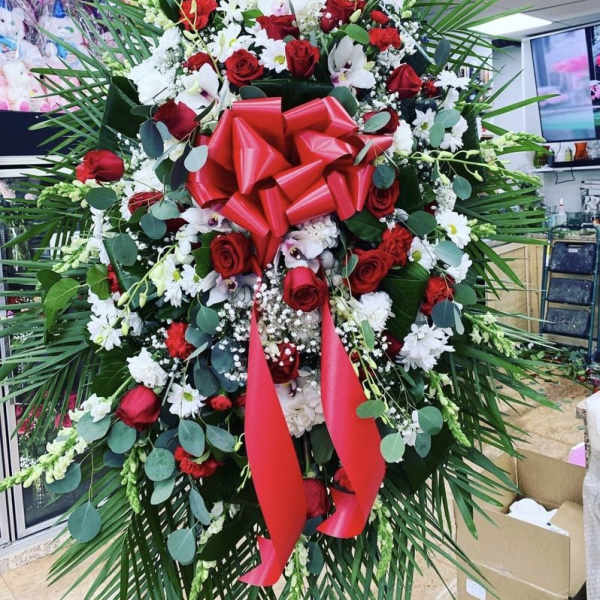 Large standing floral spray with red roses and white flowers, accented by a red bow
