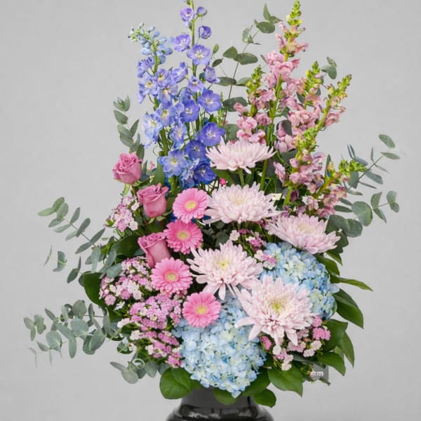 Tall pastel flower arrangement in a black urn vase