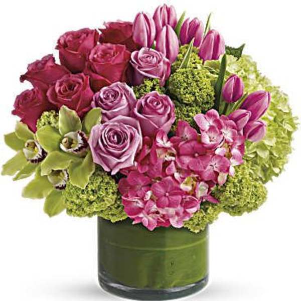 Pink roses and tulips arranged in a green glass vase