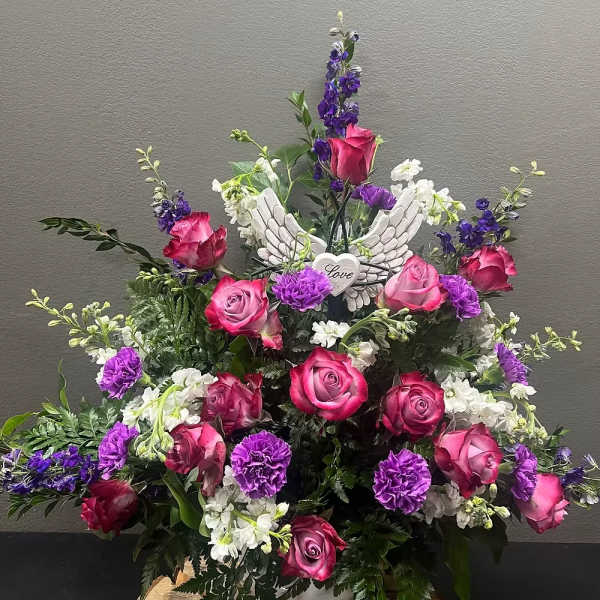Pink and purple rose arrangement with white flowers and angel wings