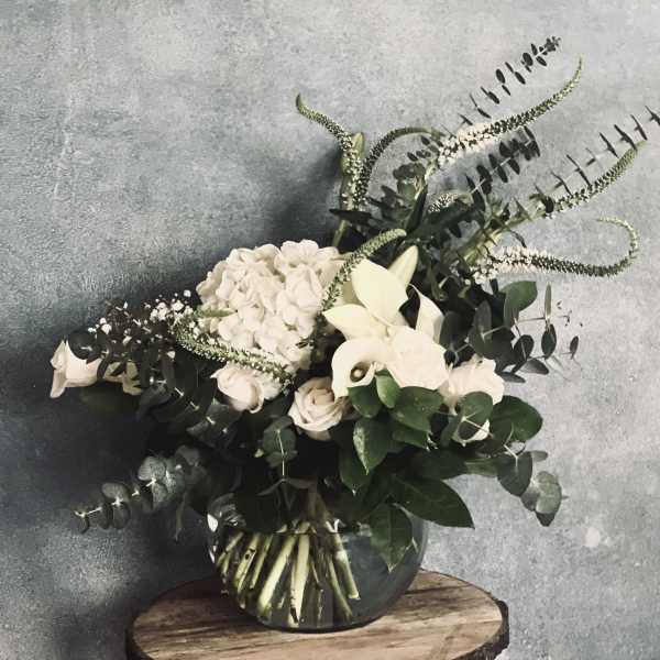 White flowers and greenery arranged in a glass vase