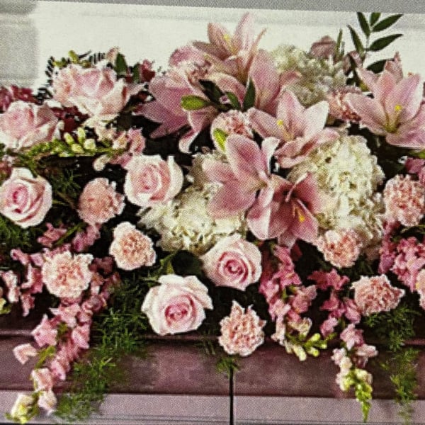 Pink and white floral arrangement with lilies and roses in a low container