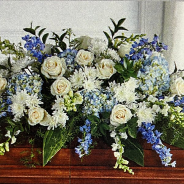 White and blue floral arrangement in a wooden casket spray