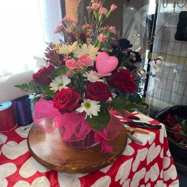 Bouquet of red roses, pink carnations, and white daisies with a pink heart pick