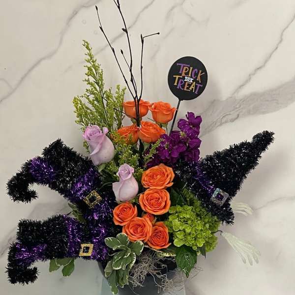 Halloween arrangement with orange and purple roses in a black container