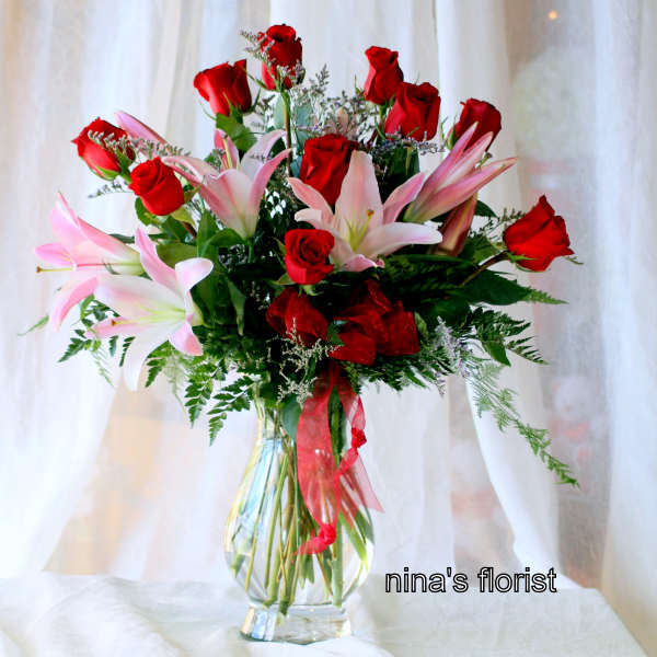 Bouquet of red roses and pink lilies in a clear glass vase