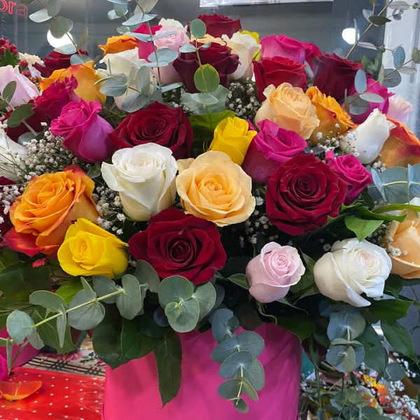 Large bouquet of multicolored roses in a pink box with eucalyptus