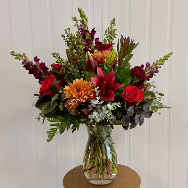 Mixed bouquet of red and orange flowers in a clear glass vase
