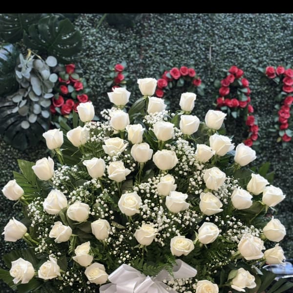 Large bouquet of white roses in a white vase with a ribbon bow