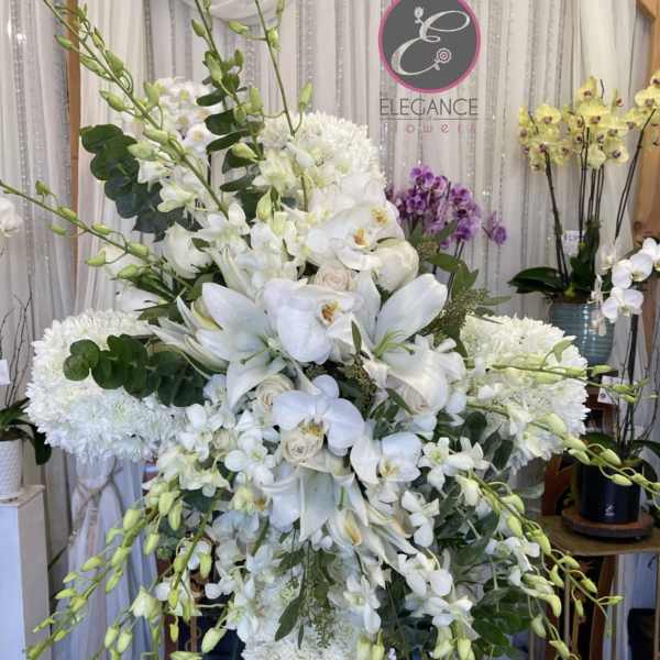 Large white floral standing arrangement with orchids and lilies