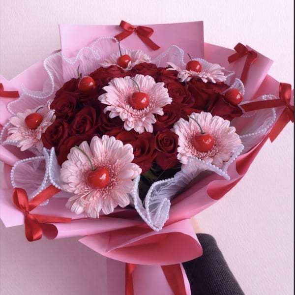 Bouquet of red roses and pale pink daisies with red ribbon accents