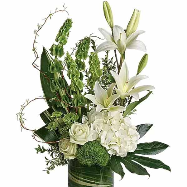 Tall white and green arrangement with lilies, hydrangeas, and roses in a clear cylinder vase