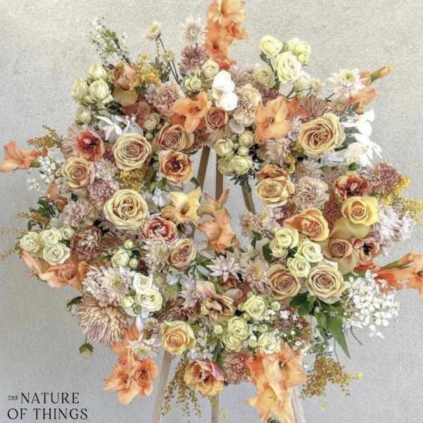 Large pastel floral wreath on a stand with roses and mixed blooms