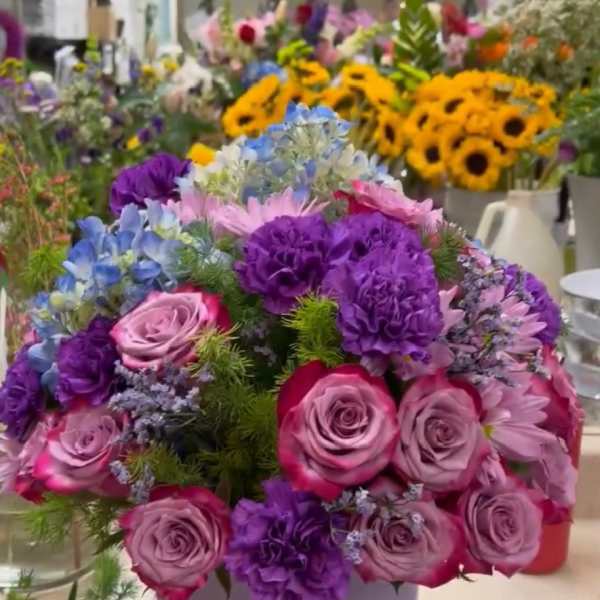 Round bouquet of pink and purple flowers in a lavender hat box