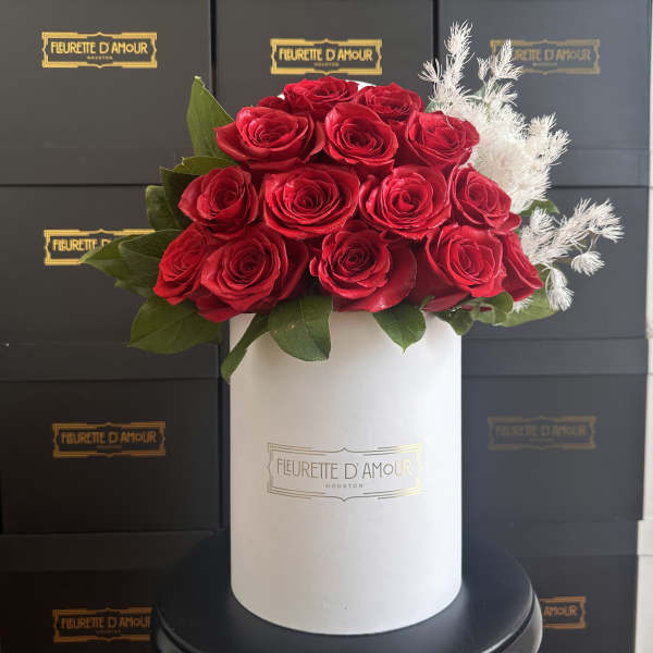 Red roses arranged in a white hat box with white filler flowers