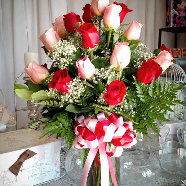 Red and pink roses in a glass vase with a ribbon bow