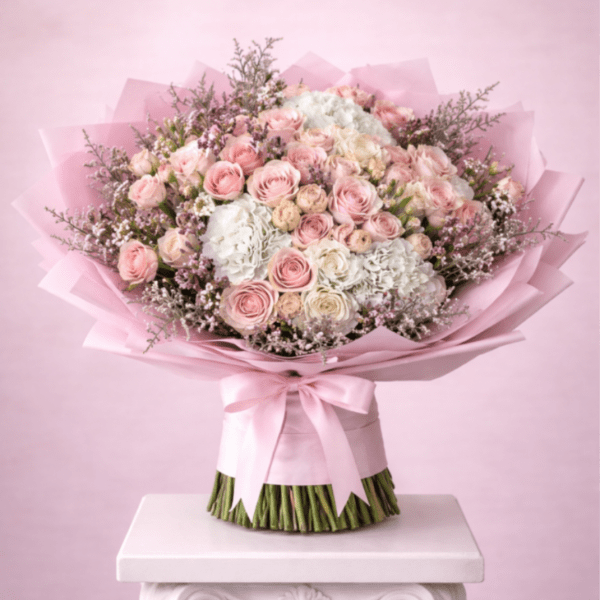 Pink and white rose bouquet wrapped in pink paper with a satin ribbon