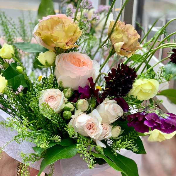 Bouquet of pale roses and yellow blooms with purple accents