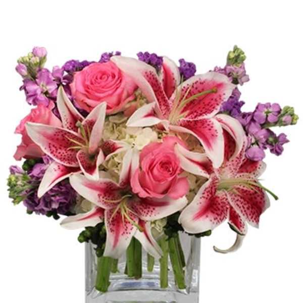 Pink roses and stargazer lilies in a clear square vase