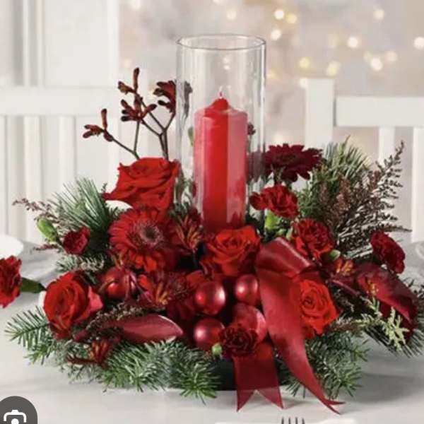 Red floral centerpiece with a tall glass candle holder and red candle