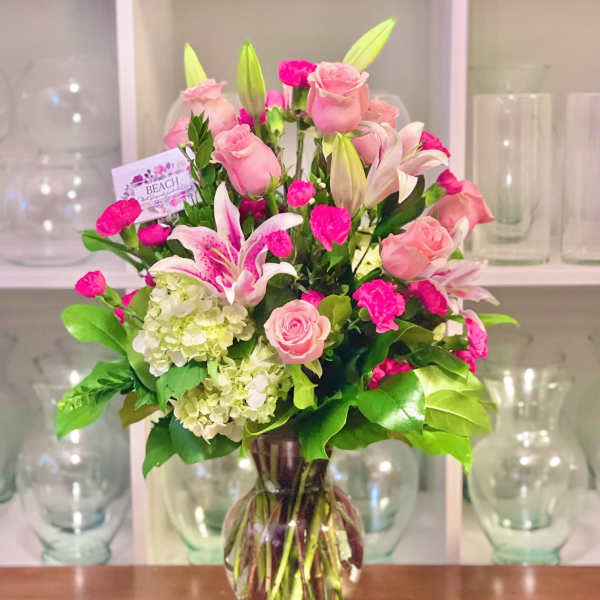 Pink roses and lilies arranged in a clear glass vase
