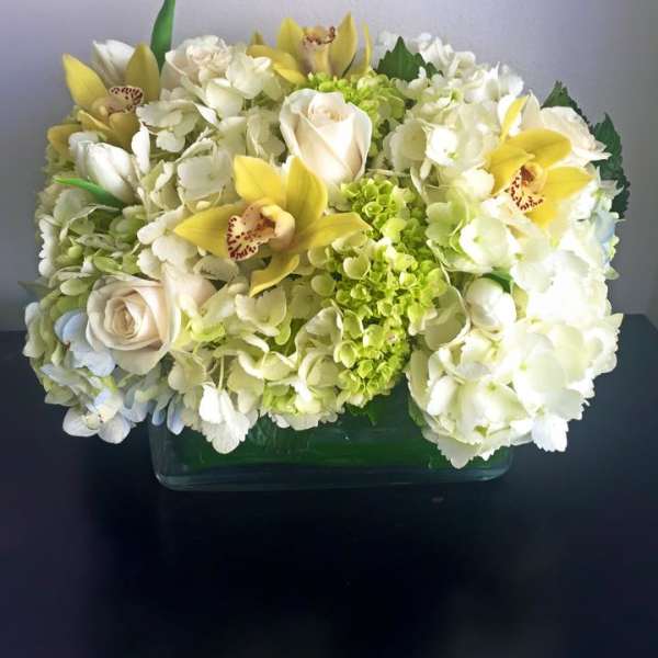 White hydrangea and roses with yellow orchids in a glass vase