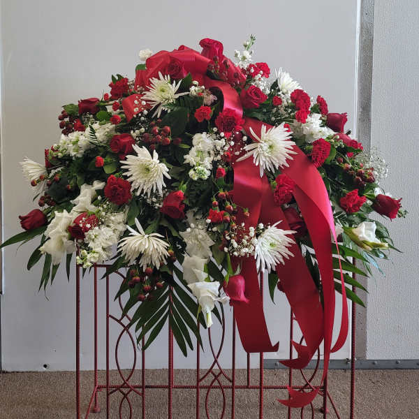 Large red and white floral spray with ribbon on a stand