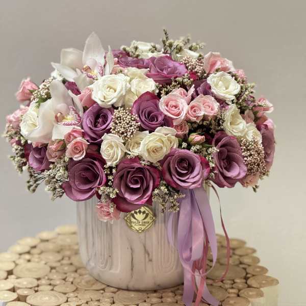 Pink and white rose arrangement in a ceramic vase with a ribbon