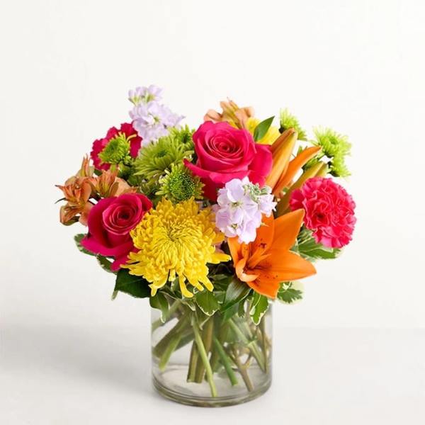 Mixed bouquet of roses, lilies, and chrysanthemums in a glass vase