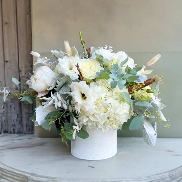 White floral arrangement in a white cylindrical vase
