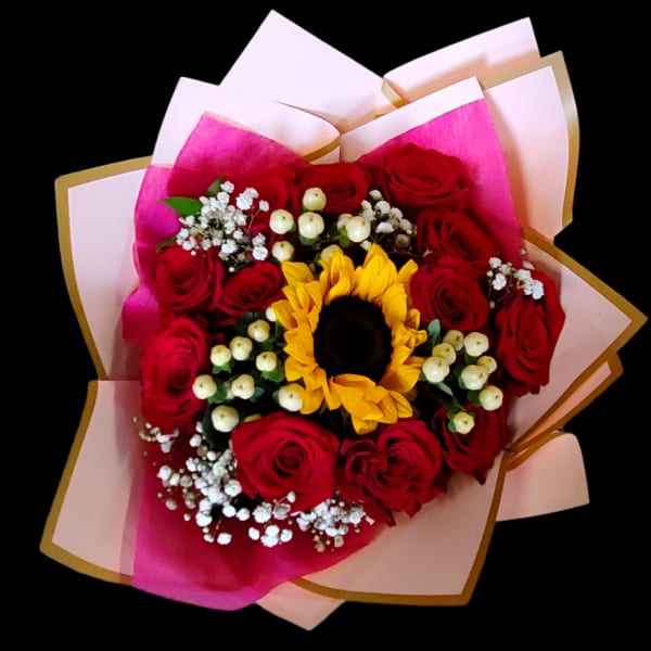 Bouquet of red roses with a sunflower center and pink wrapping