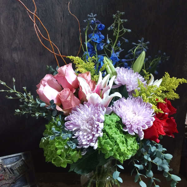 Mixed bouquet in a glass vase with pink roses, lavender mums, and lilies