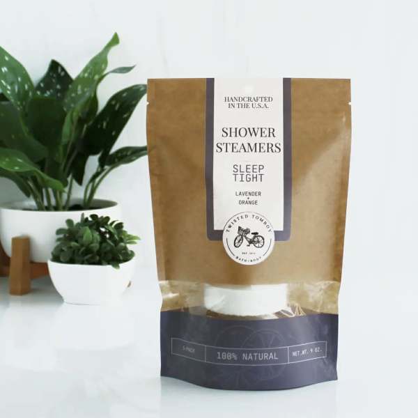 Package of shower steamers beside two potted plants