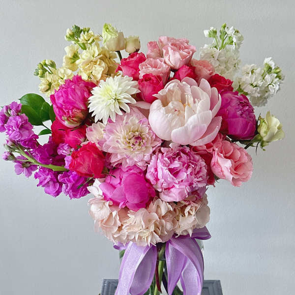 Pink and white mixed bouquet in a glass vase with a lavender ribbon