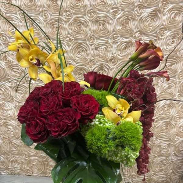 Bouquet of burgundy roses and yellow orchids in a mirrored vase