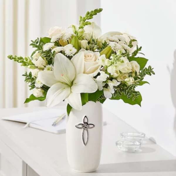 White floral arrangement in a tall vase with a cross emblem
