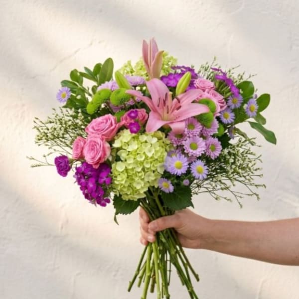 Handheld bouquet of pink lilies, roses, and purple flowers