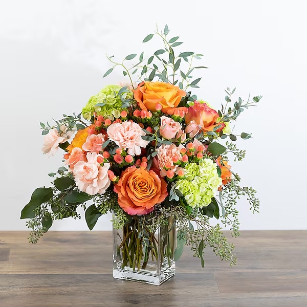 Orange and peach bouquet in a clear glass vase
