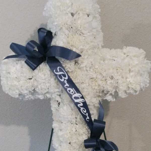 White floral cross on an easel with navy ribbons