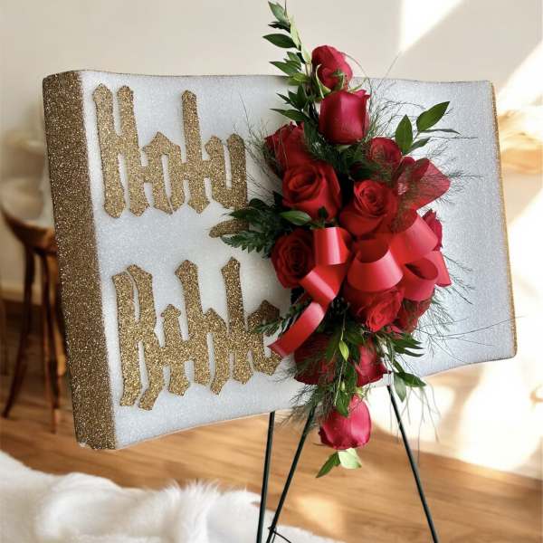 Red rose arrangement on a glittery display board with gold lettering