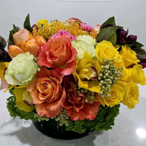 Colorful bouquet of roses, tulips, and orchids in a black vase